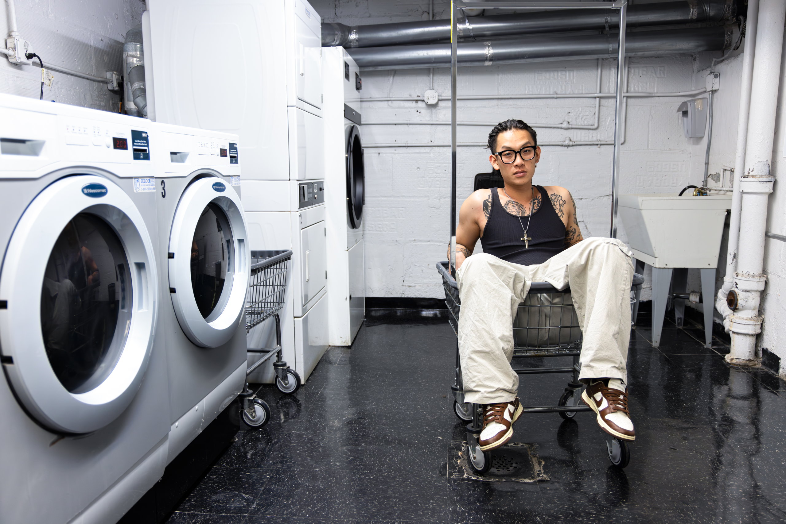 A man seated among washing machines in a laundromat — Win or Lose