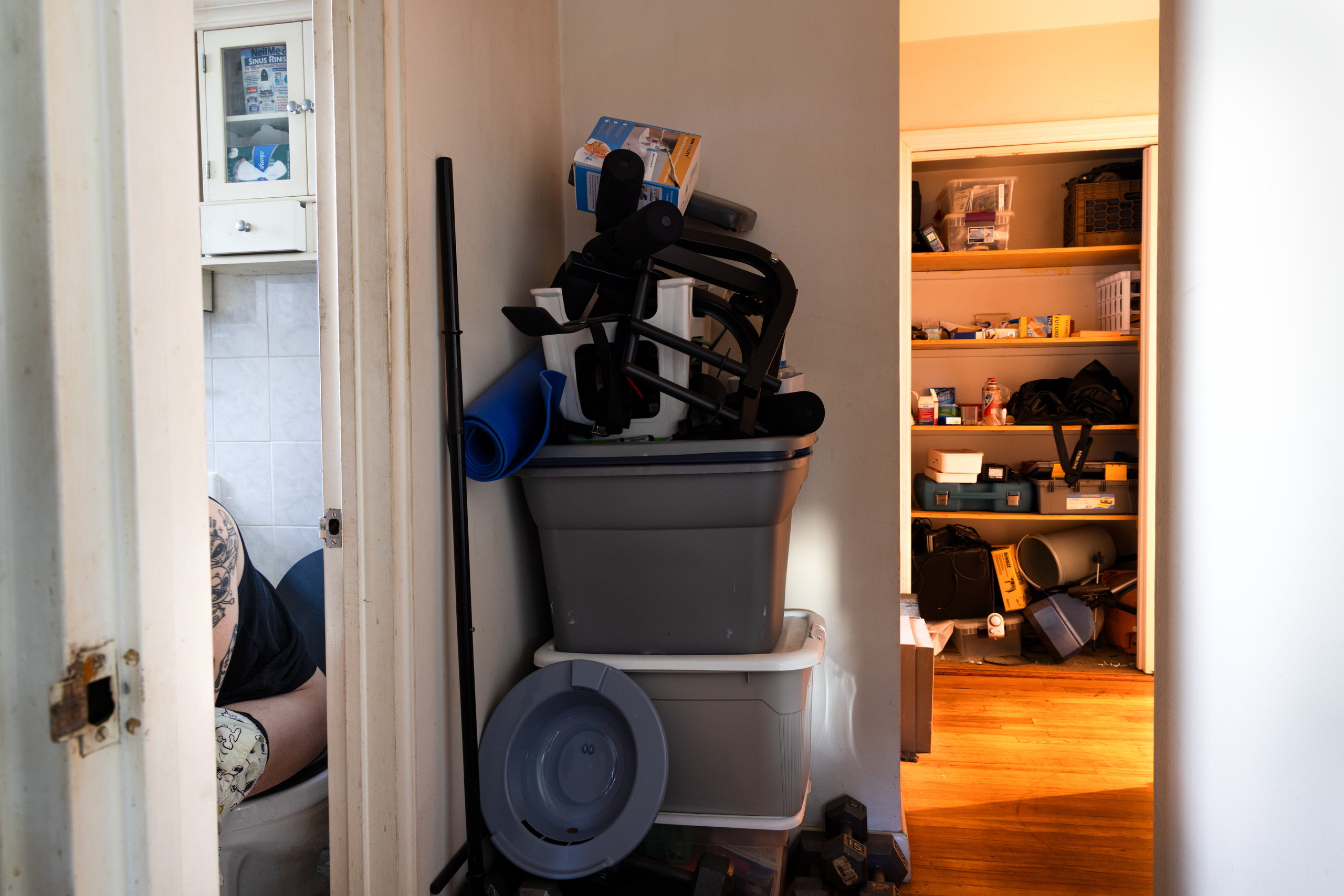 A crowded room of stacked storage bins and belongings, a doorway opening to shelves beyond — Win or Lose