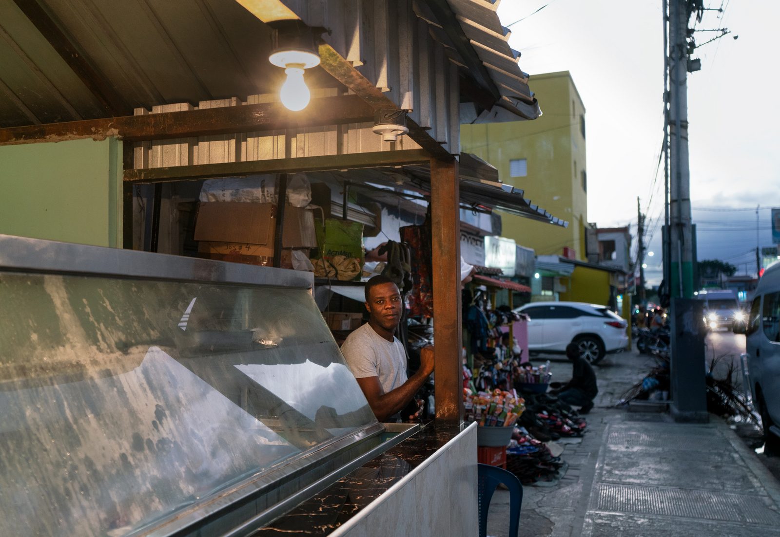 A man standing in the opening of a street food stall at dusk — Punta Cana