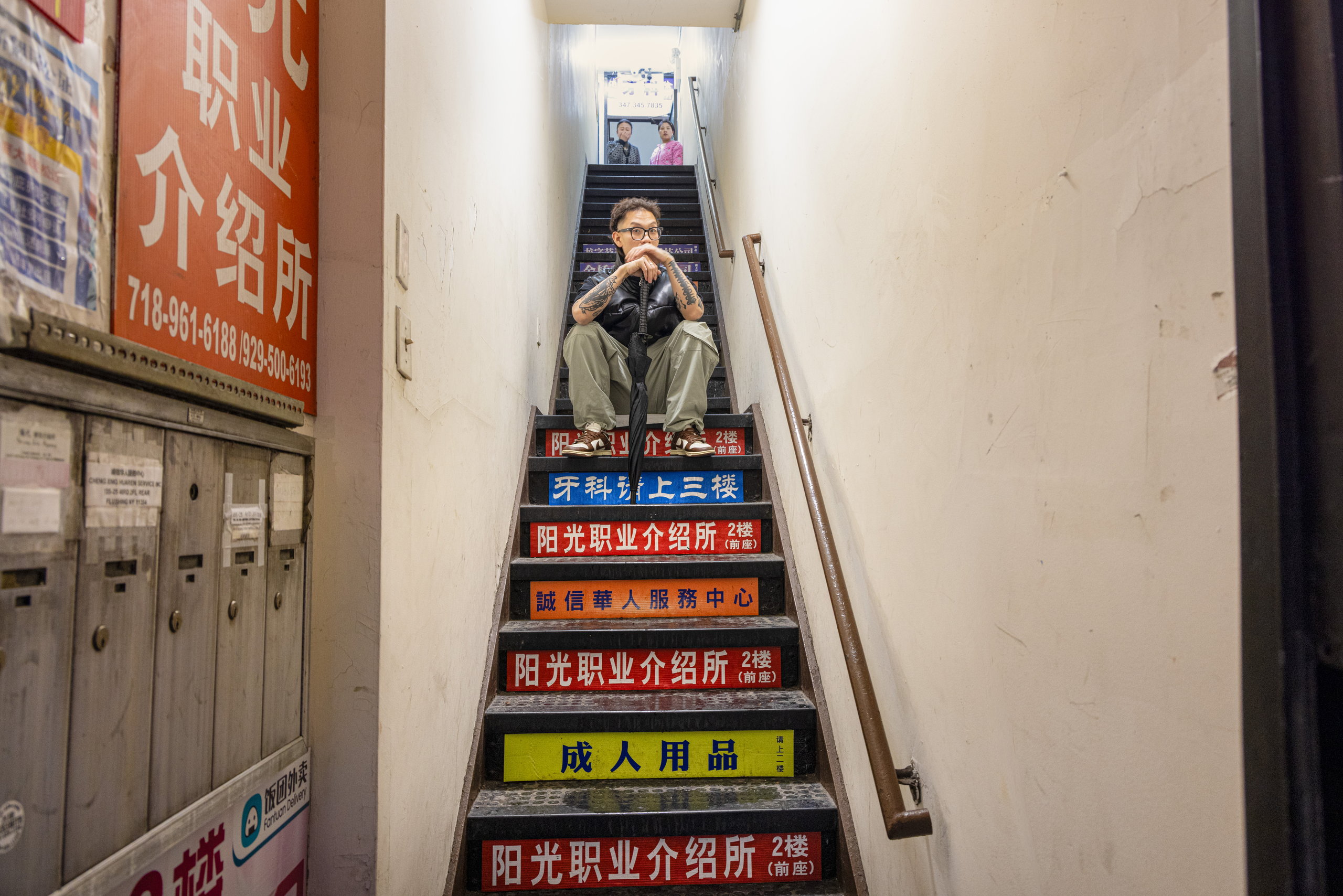 A man seated on a stairway lined with colourful signs — Win or Lose