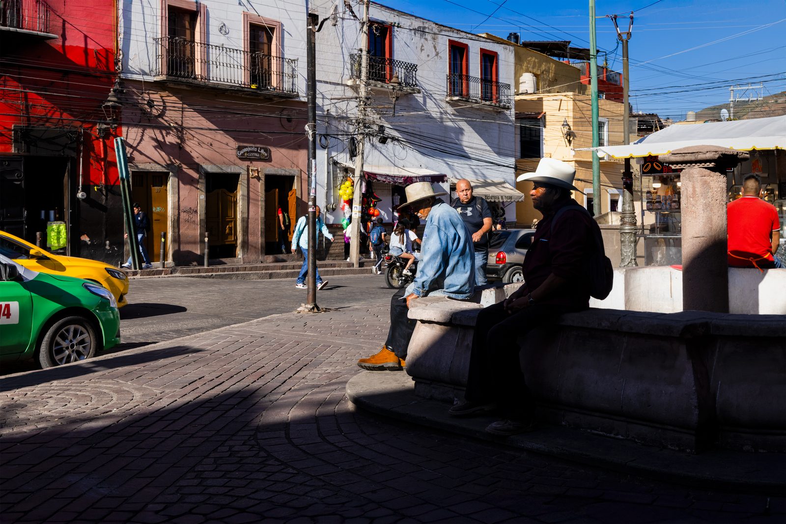 People resting on a bench in a town plaza — The Liminal Innocence
