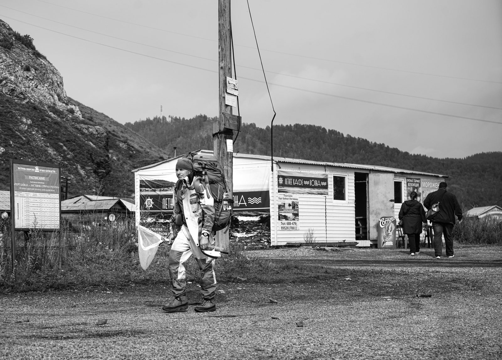 Black-and-white view of a small station building, figures waiting outside — Lake Baikal